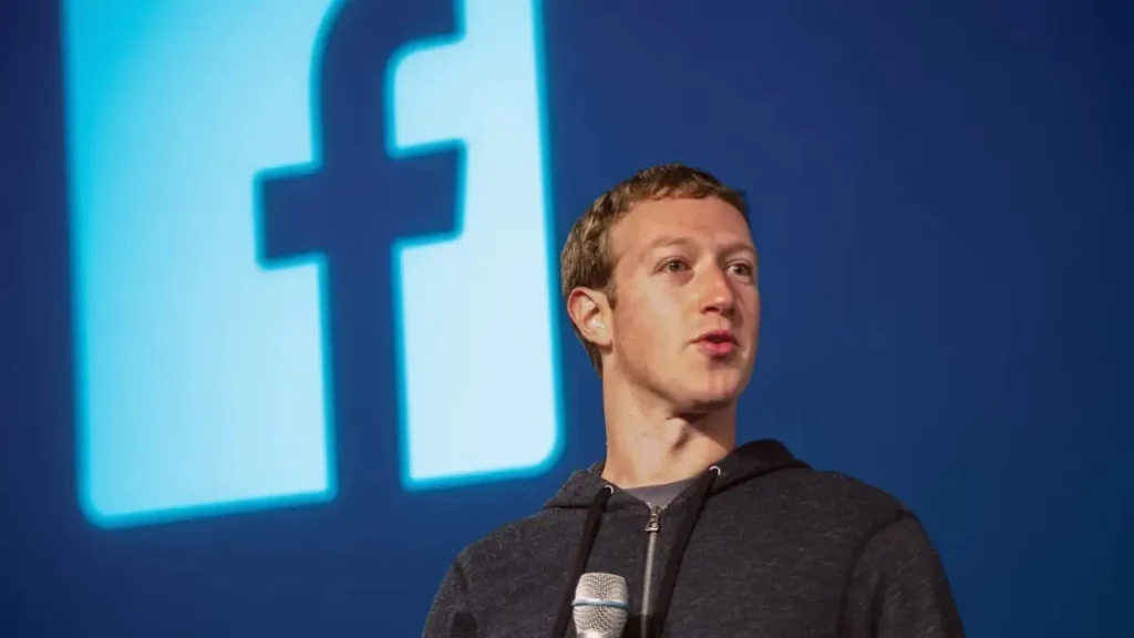 Mark Zuckerberg speaking in front of the Facebook logo.